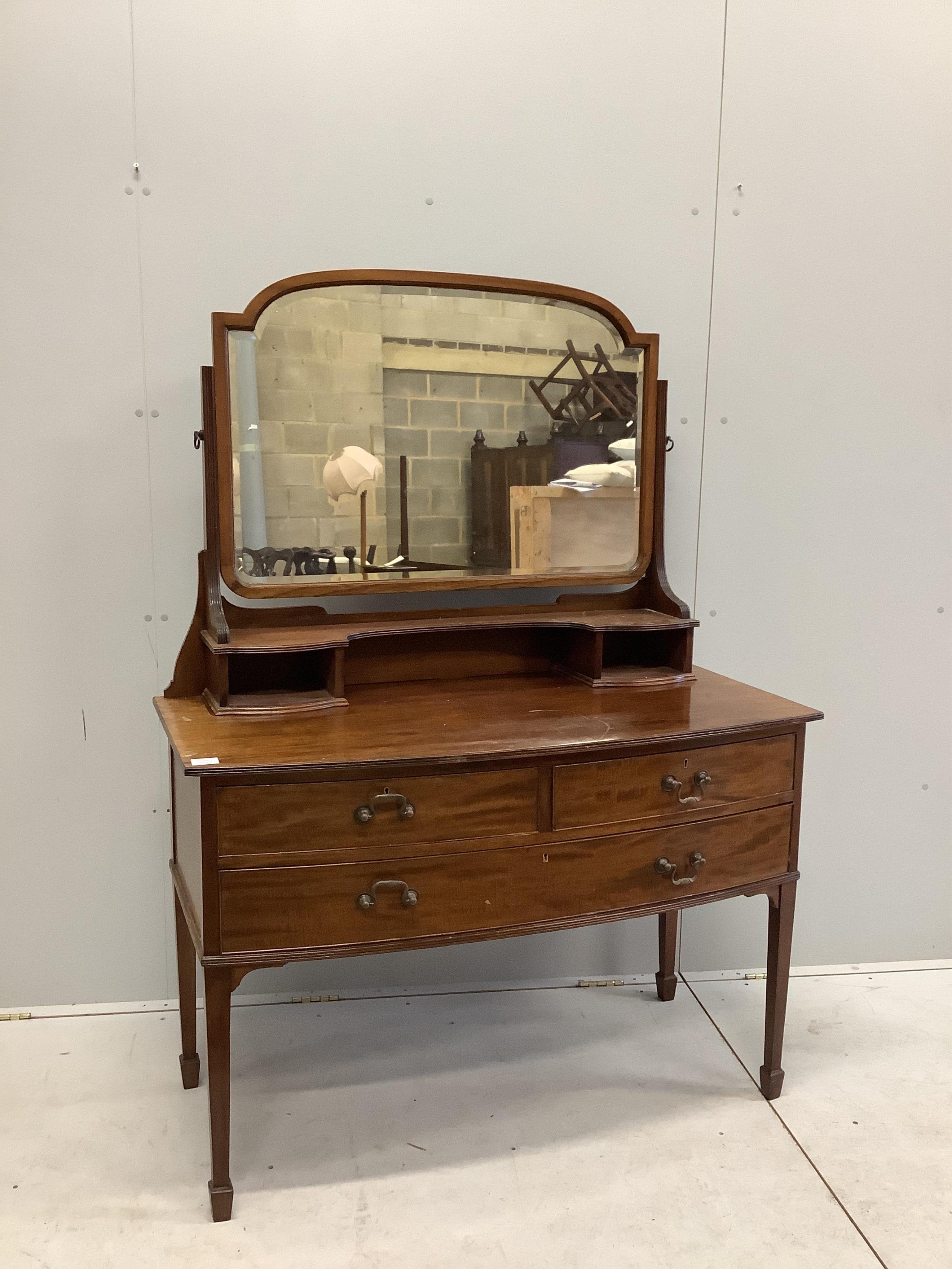 An early 20th century mahogany bowfront dressing table, fitted two short and one long drawer with brass loop handles and square tapered legs with spade feet, width 116cm, depth 57cm, height 156cm. Condition - fair